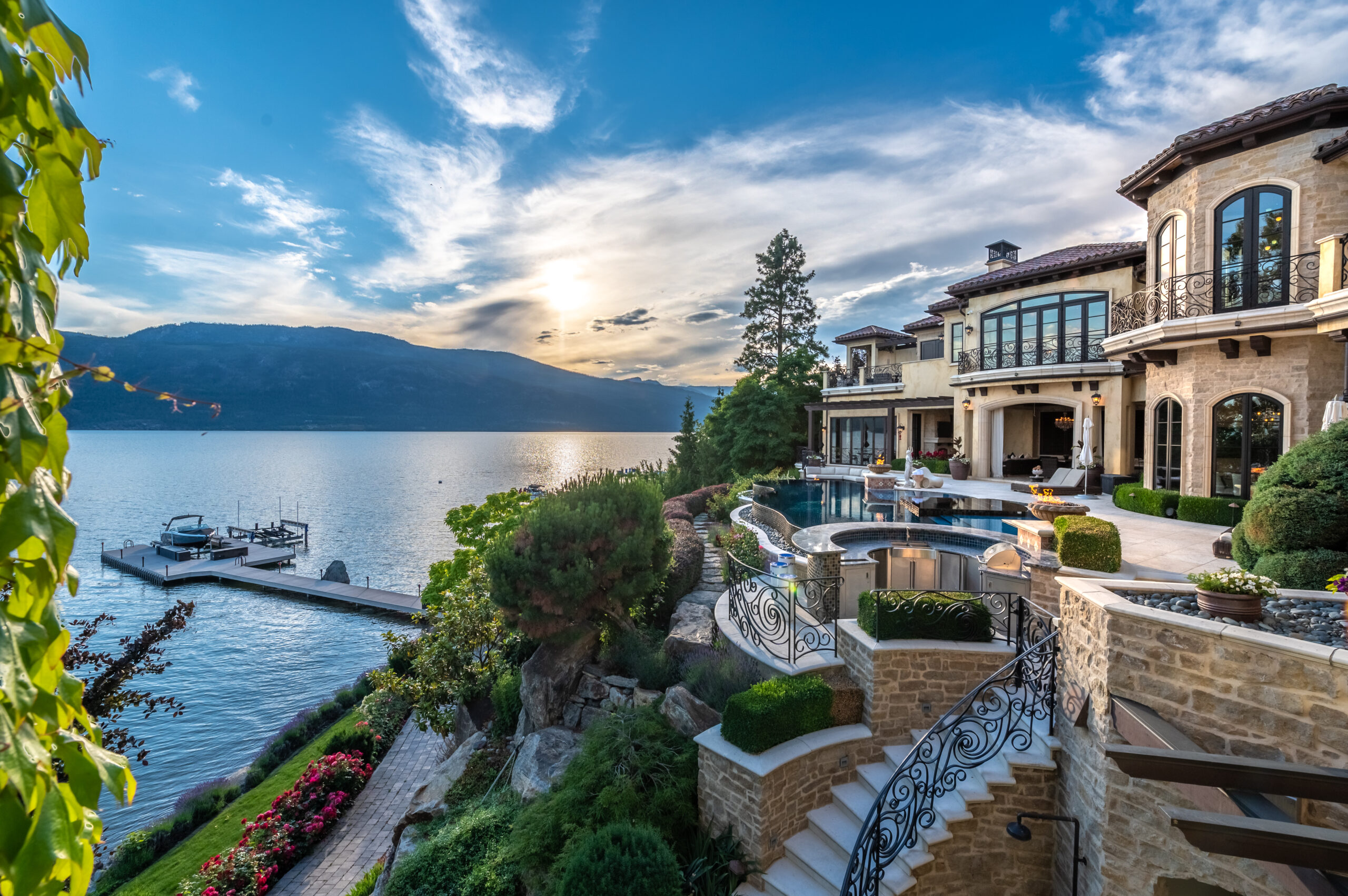 Aerial view of luxury Okanagan lakefront estate with manicured grounds, pool, and mountain views