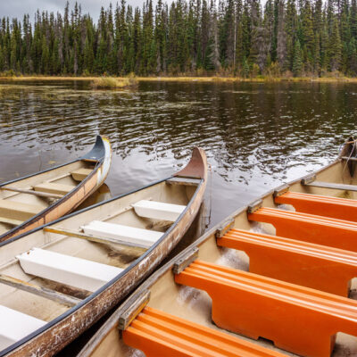 Canoes moored in McGillivray Lake in the Shuswap Highlands in central British Columbia with surrounding trees reflecting on the water